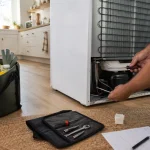 Réparation d’un réfrigérateur en cuisine avec outils et courses gardées au frais