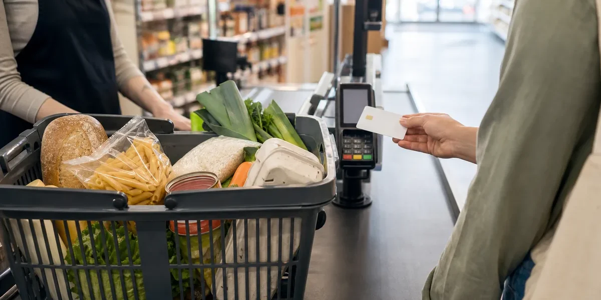 Panier de courses alimentaires posé sur un tapis de caisse avec carte titre restaurant