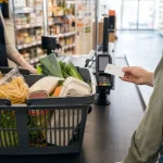 Panier de courses alimentaires posé sur un tapis de caisse avec carte titre restaurant